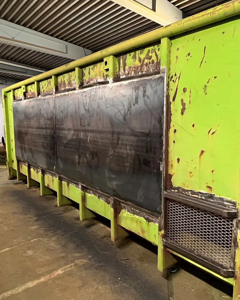 Grön lastväxlarcontainer med nya insvetsade stålplåtar i sidan
