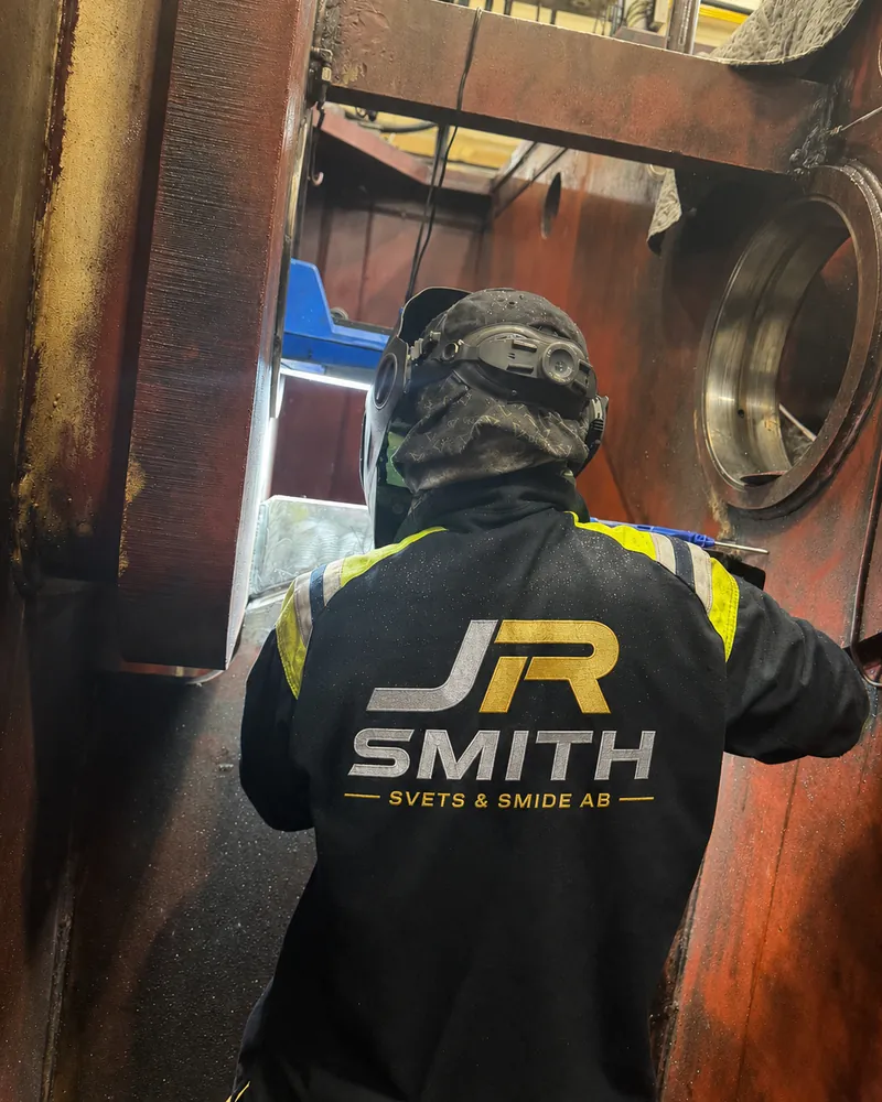 Svetsare i JR Smith-jacka svetsar inuti en kraftig stålstomme på en industrimaskin