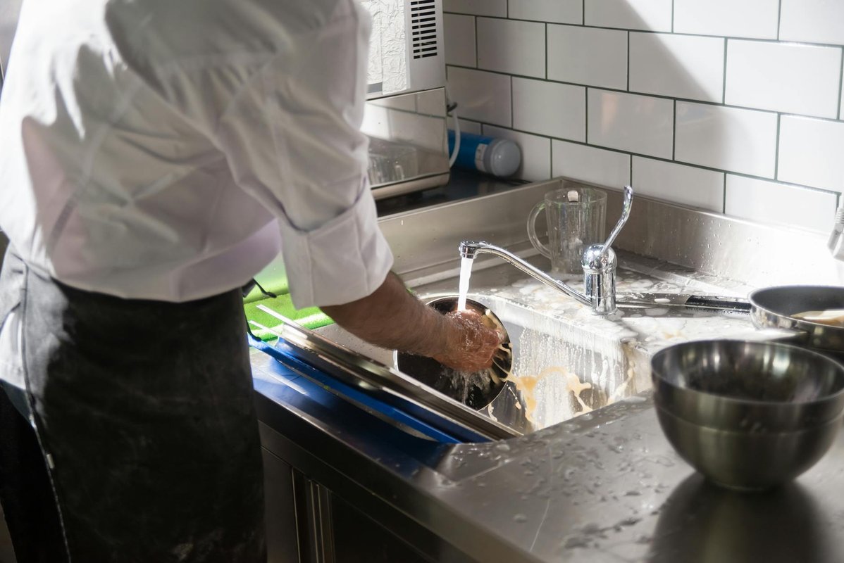 Professionell kock som arbetar i ett rent restaurangkök med rostfri inredning