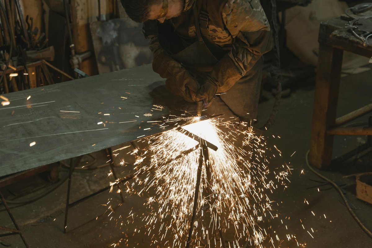 Svetsare som tillverkar ett specialdesignat metallbord i en verkstad.