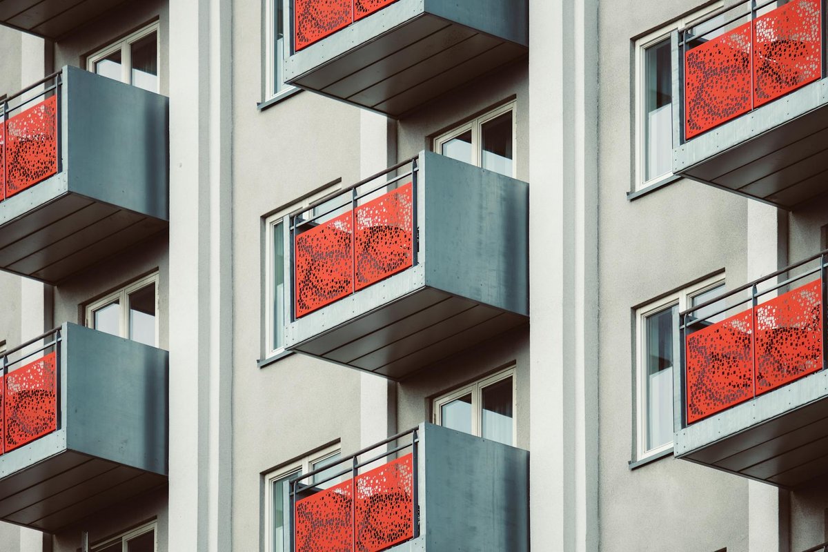 Ett modernt balkongräcke i rostfritt stål med glaspartier, monterat på en fastighet.