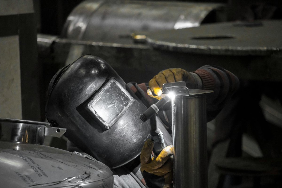 Erfaren svetsare fogar samman en metallbänk i verkstaden med TIG-svetsning.