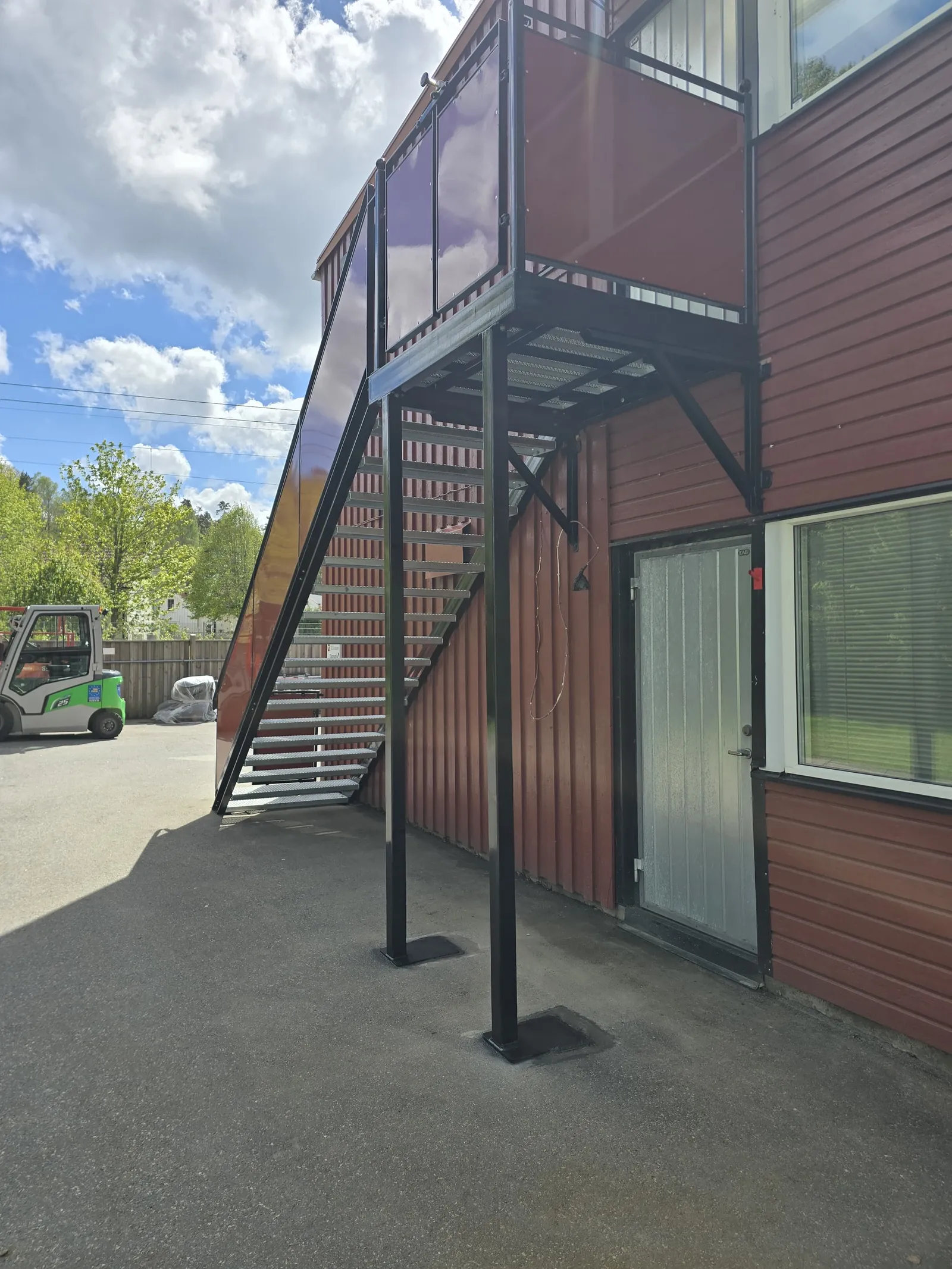 Utvändig röd ståltrappa med räcke monterad på en kommersiell byggnad